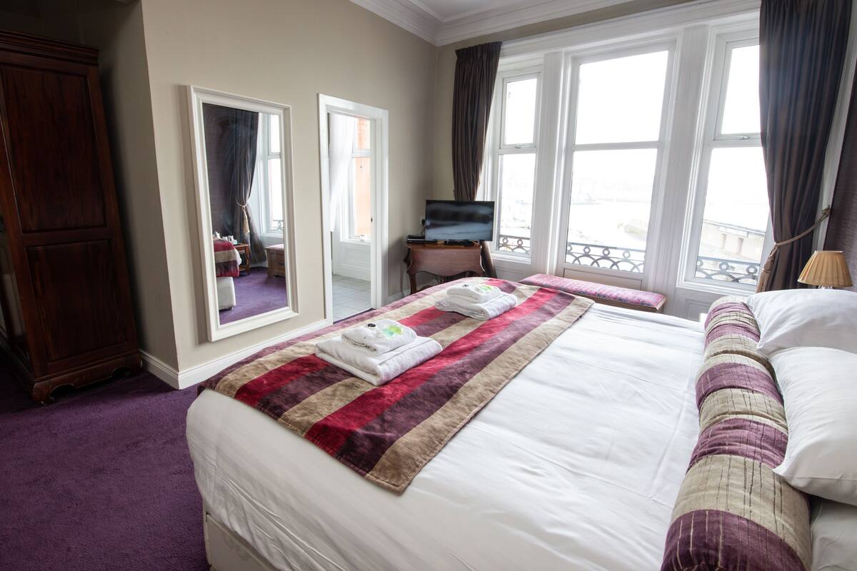 Une chambre d’hôtel avec un grand lit, une commode, une télévision et un balcon avec vue.