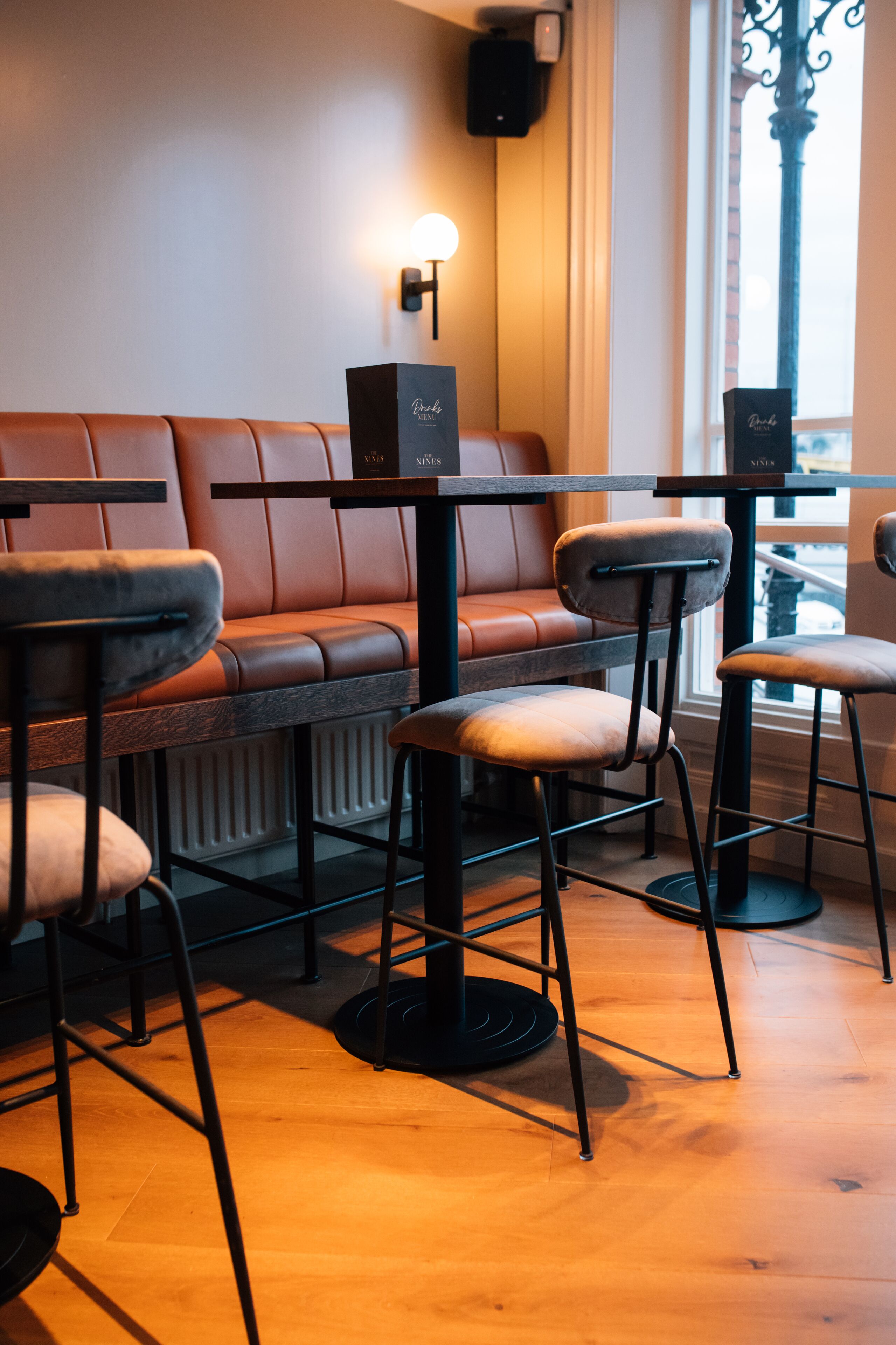 A restaurant interior with a leather booth seating area, bar stools, and a table with a menu.