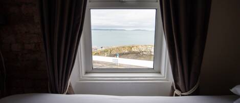 A bedroom with a view of the sea through a window.