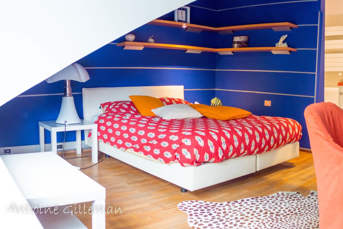 A bedroom with a bed, a desk, and a chair.