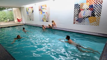 Una piscina techada, sombrillas, sillones reclinables de piscina