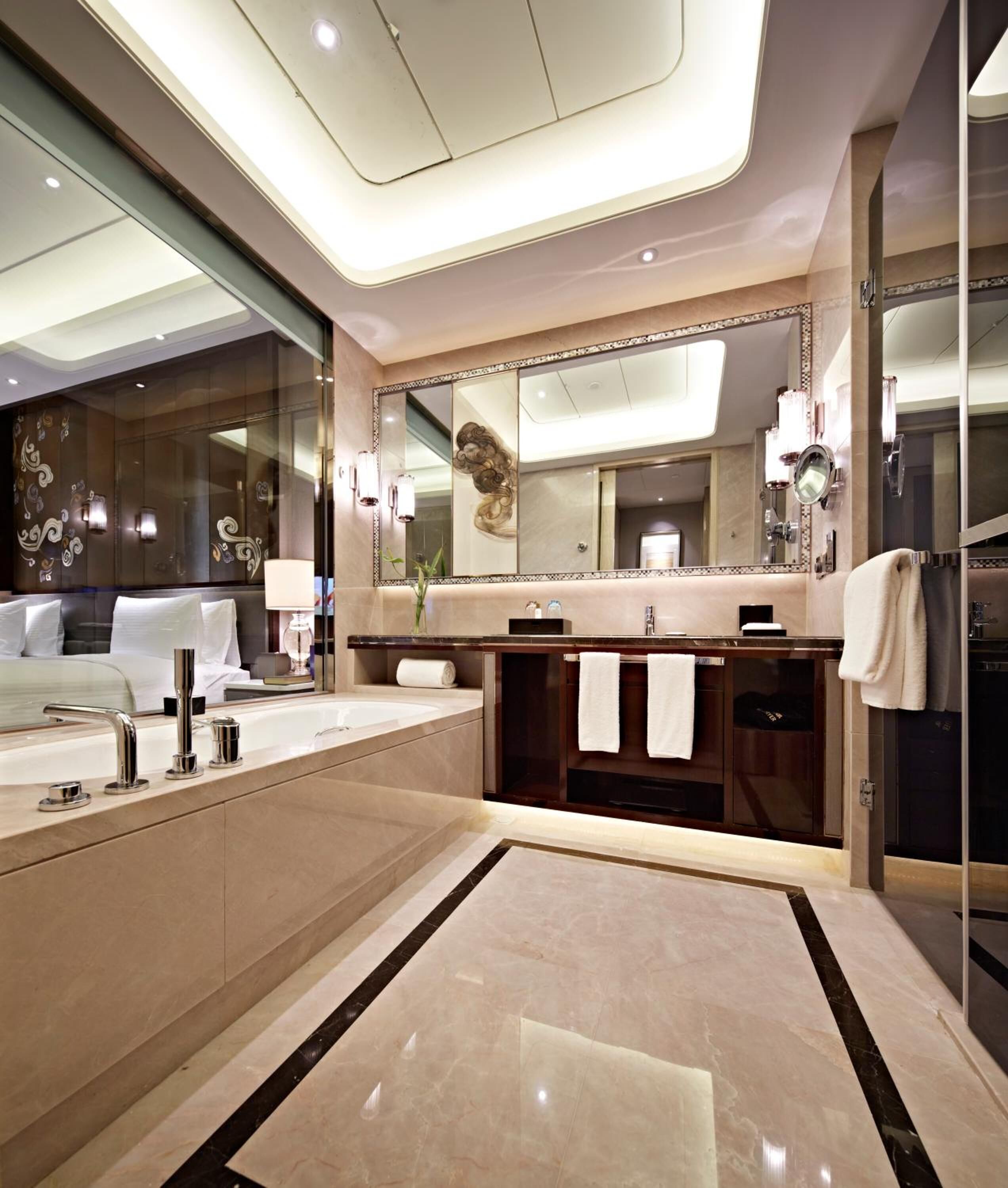 Une salle de bain moderne dotée d’un grand miroir, de deux vasques et d’une douche à l’italienne.