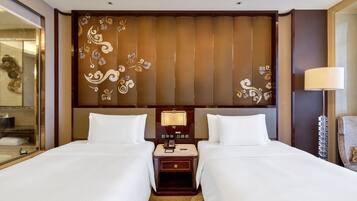 Habitación de hotel con dos camas, cabecero de madera con diseños decorativos, mesita de noche con lámpara y un espejo.