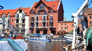 Ein Gebäude am Wasser mit mehreren Balkonen und einem angedockten Boot.