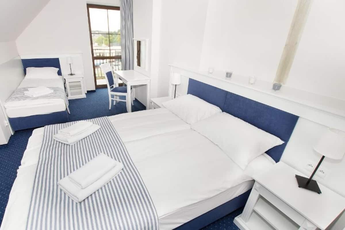A hotel room with a large bed, a smaller bed, a desk, and a chair.