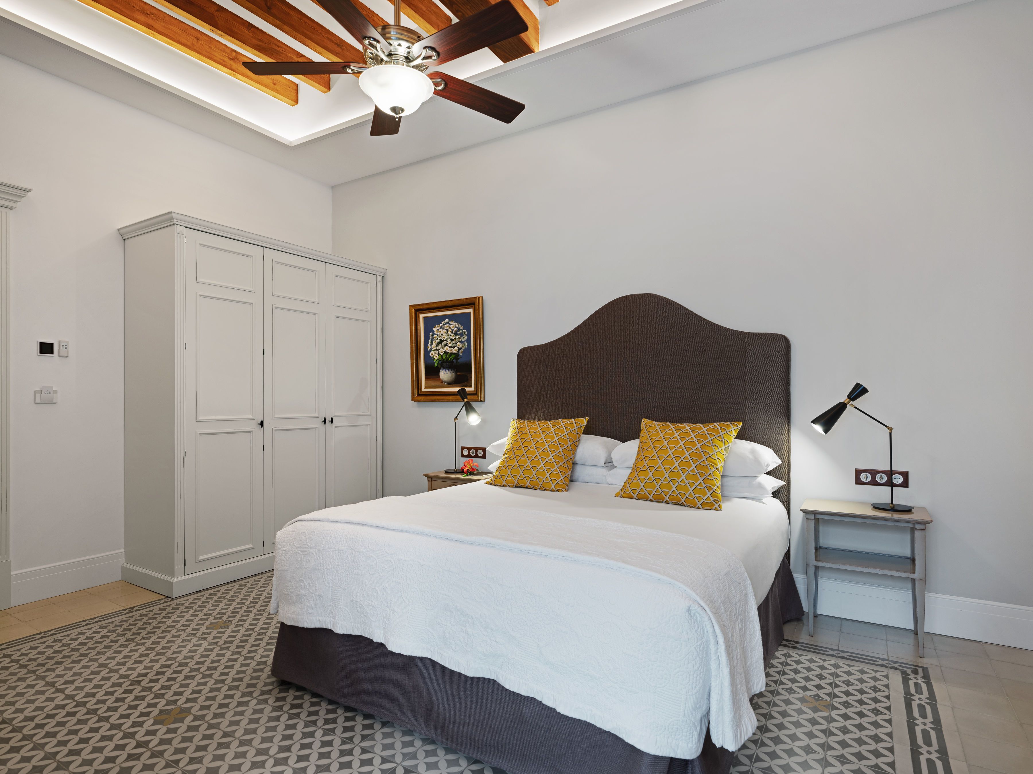 Un dormitorio con una cama, una mesita de noche, una lámpara, un ventilador de techo y un armario.