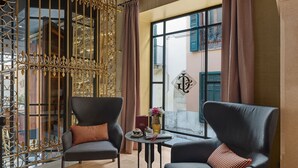 A room with two armchairs, a small round table with a vase and a book, and a window with shutters. - Hotel Glòria de Sant Jaume (Palma de Mallorca)