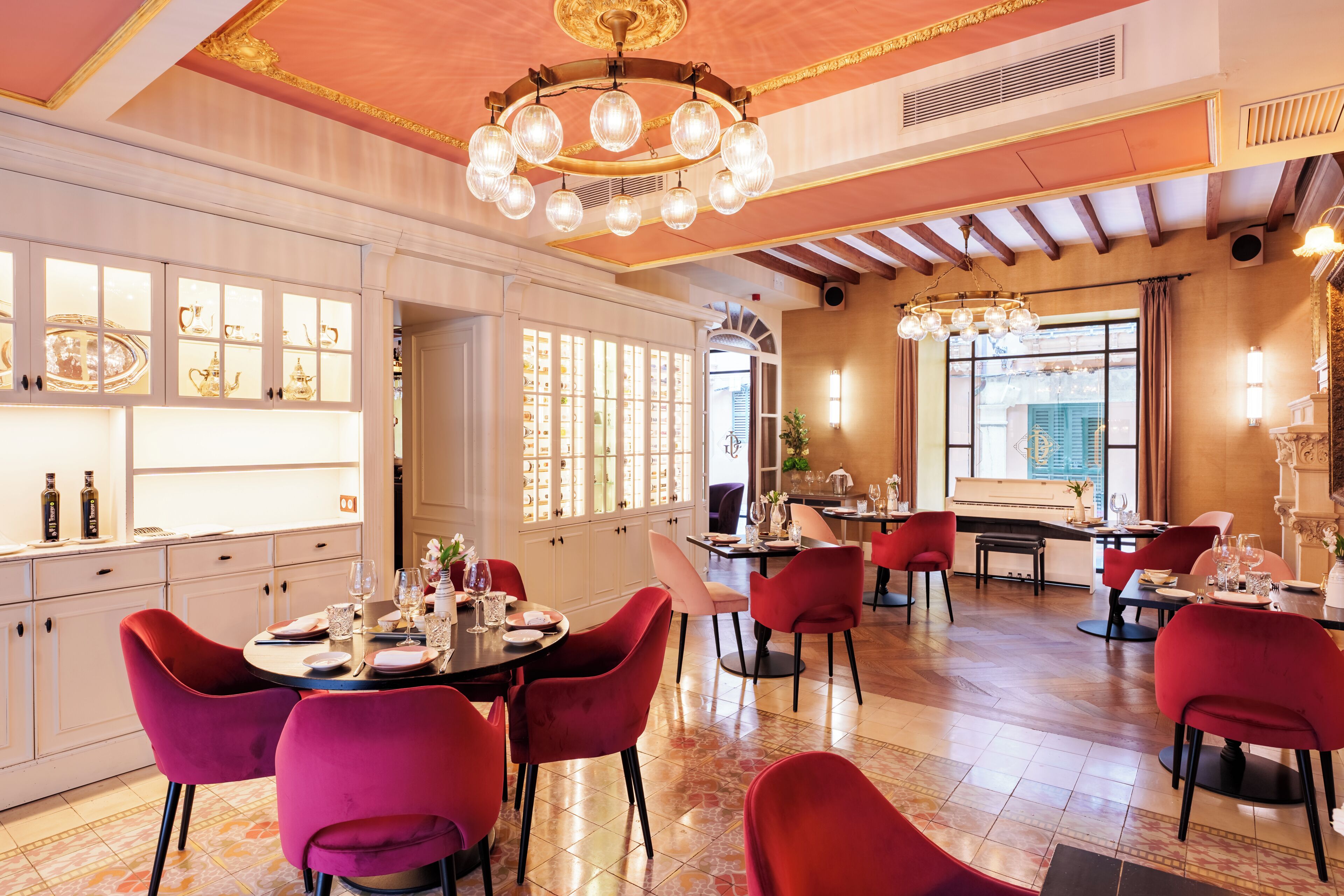 Un comedor bien iluminado con sillas rojas, un piano y un amplio ventanal con vistas.