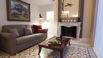 Una sala de estar con un sofá, una mesa de centro con fruta, una chimenea y un cuadro en la pared.