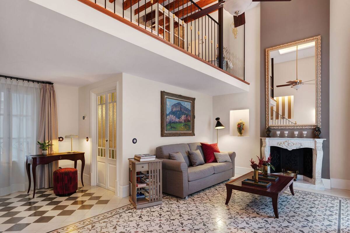 Ein Wohnzimmer mit Schachbrettmuster-Boden, einer Couch, einem Couchtisch, einem Kamin und einer Treppe.