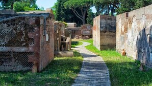 An ancient brick pathway leading through ruins with stone structures and greenery. - Il Mare di Roma (Rome)