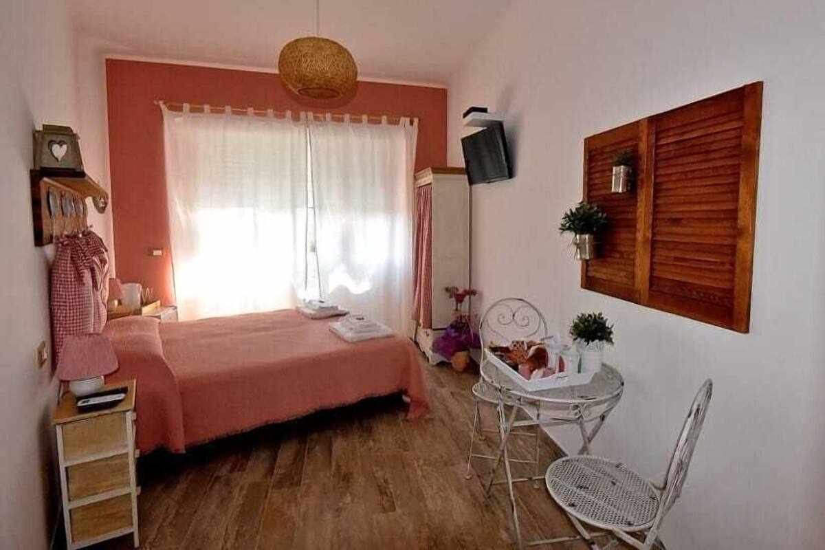 Ein Schlafzimmer mit Bett, Nachttisch, Sessel und einem kleinen Tisch mit Dekoration.