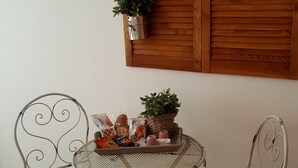A dining area with two metal chairs and a round table, featuring a wooden wall panel with two potted plants. - Il Mare di Roma (Rome)