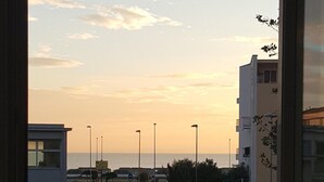 A street view with parked cars, buildings, and a sunset sky. - Il Mare di Roma (Rome)