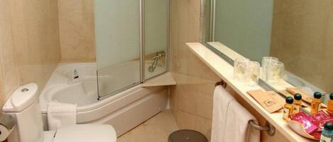 Un baño con bañera, inodoro, lavabo y ducha con mampara de vidrio.