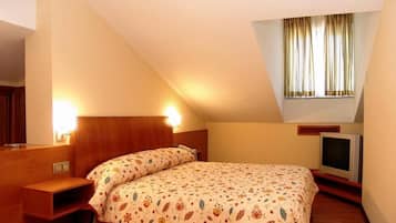 A bedroom with a bed, a bedside table, a TV, and a window with curtains.