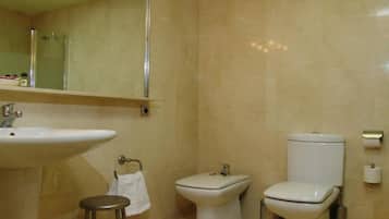 Un baño con un lavamanos grande, inodoro, bidé y espejo.