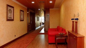 Un passadís d'hotel amb un sofà vermell, mobles de fusta i quadres a les parets.