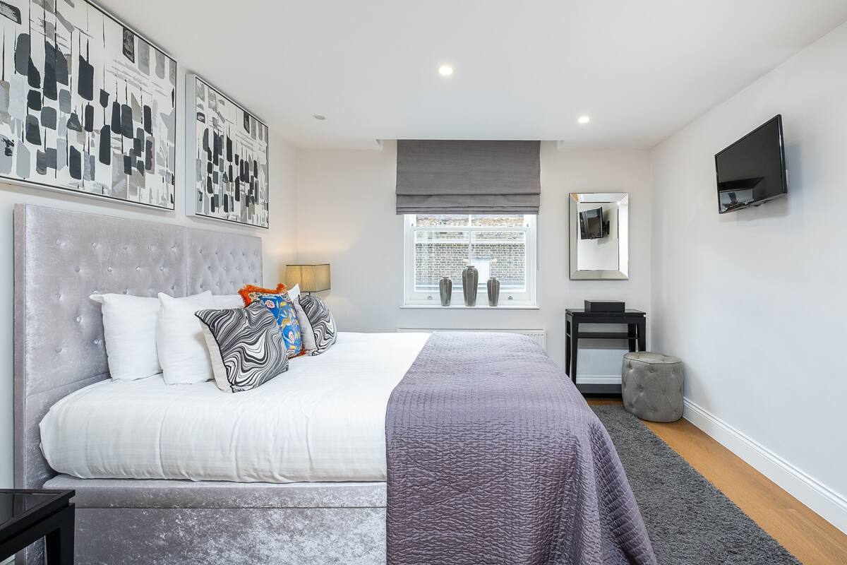 Une chambre à coucher moderne avec un grand lit, un téléviseur à écran plat et des œuvres d’art accrochées aux murs.