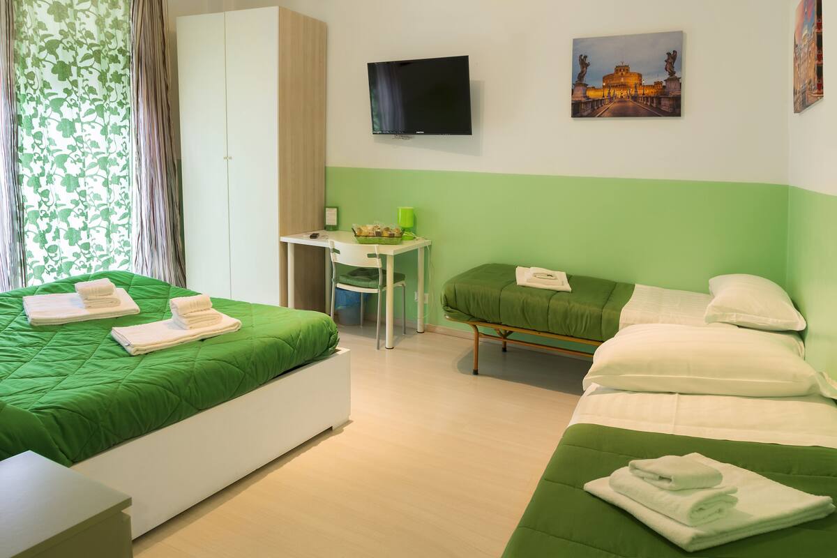 A hotel room with two beds, a desk, a TV, and a painting on the wall.