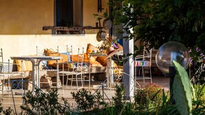 An outdoor seating area with metal furniture, a stone bench, and a variety of cushions. - The Old Farm Asfodeli - Adults Only (Loiri Porto San Paolo)