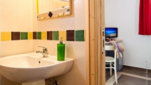 A bathroom with a sink, mirror, and a television in the background. - The Old Farm Asfodeli - Adults Only (Loiri Porto San Paolo)