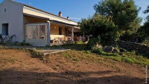A single-story house with a covered porch, a stone wall, and a small garden area. - The Old Farm Asfodeli - Adults Only (Loiri Porto San Paolo)