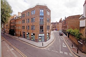 A corner building with multiple ground-floor retail spaces, including a cafe.