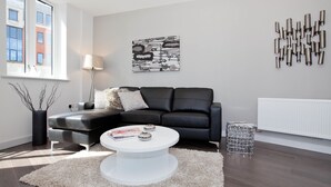 A modern living room with a black leather sofa, a white coffee table, and a minimalist decor. - One Whites Row (London)