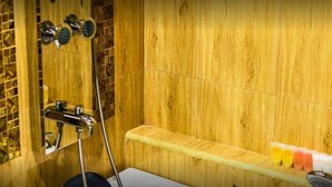 Un box de ducha de madera con un banco, un cabezal de ducha de mano y un cabezal de ducha instalado en la pared.