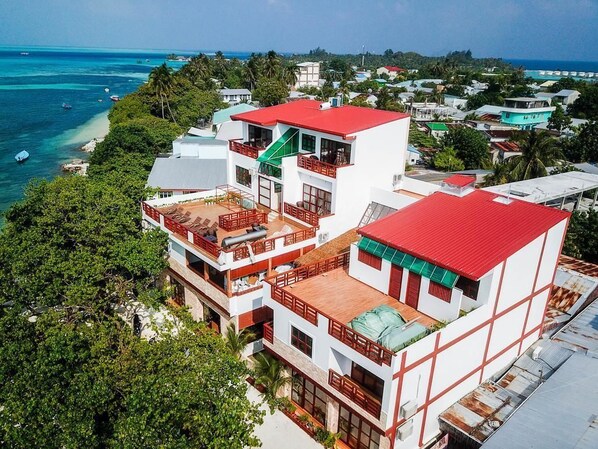 Un immeuble à plusieurs étages, doté d’un toit rouge, de balcons et offrant une vue sur l’océan.