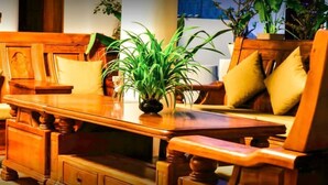 Un juego de comedor de madera con una mesa central y sillas a juego, un jarrón con plantas verdes y un cojín en el lado derecho.