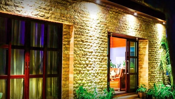 Un edificio de piedra con un gran ventanal y una puerta que da a una zona de estar al aire libre.