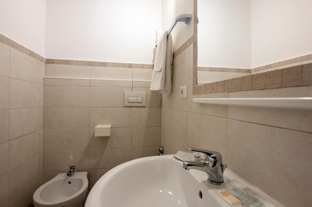 Un baño con bidé, lavamanos, toallero y espejo.