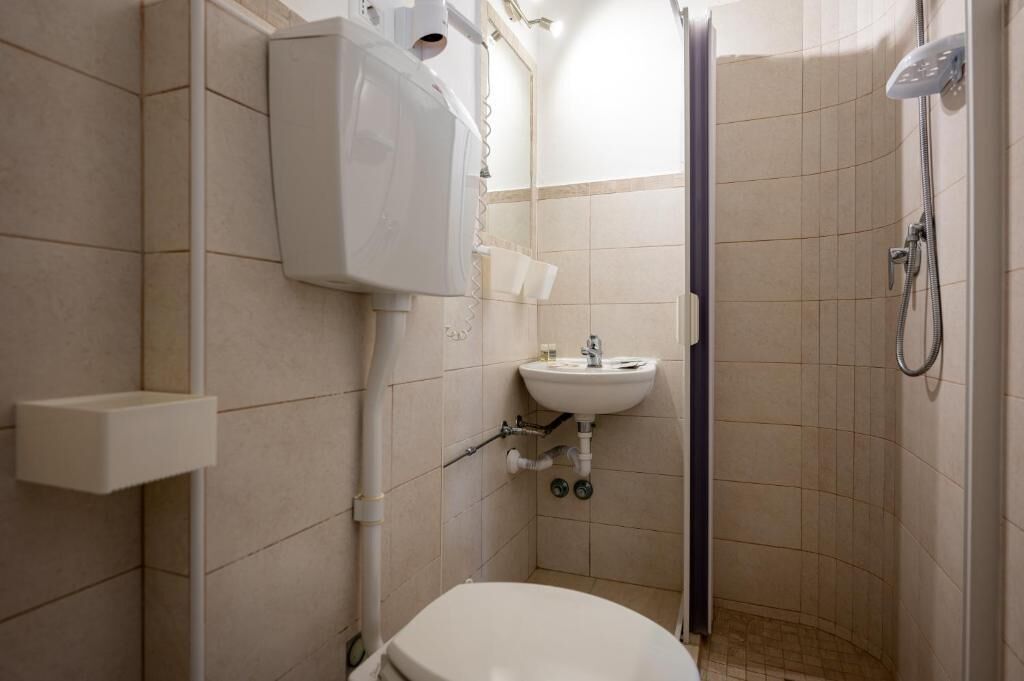 A small, compact bathroom with a toilet, sink, and shower.