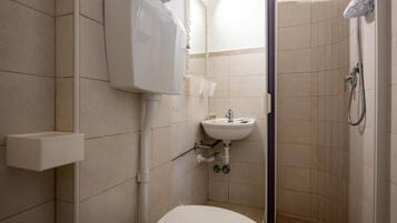 A small, compact bathroom with a toilet, sink, and shower.