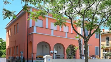Un edificio rosa con ventanas arqueadas y una entrada protegida por una reja.