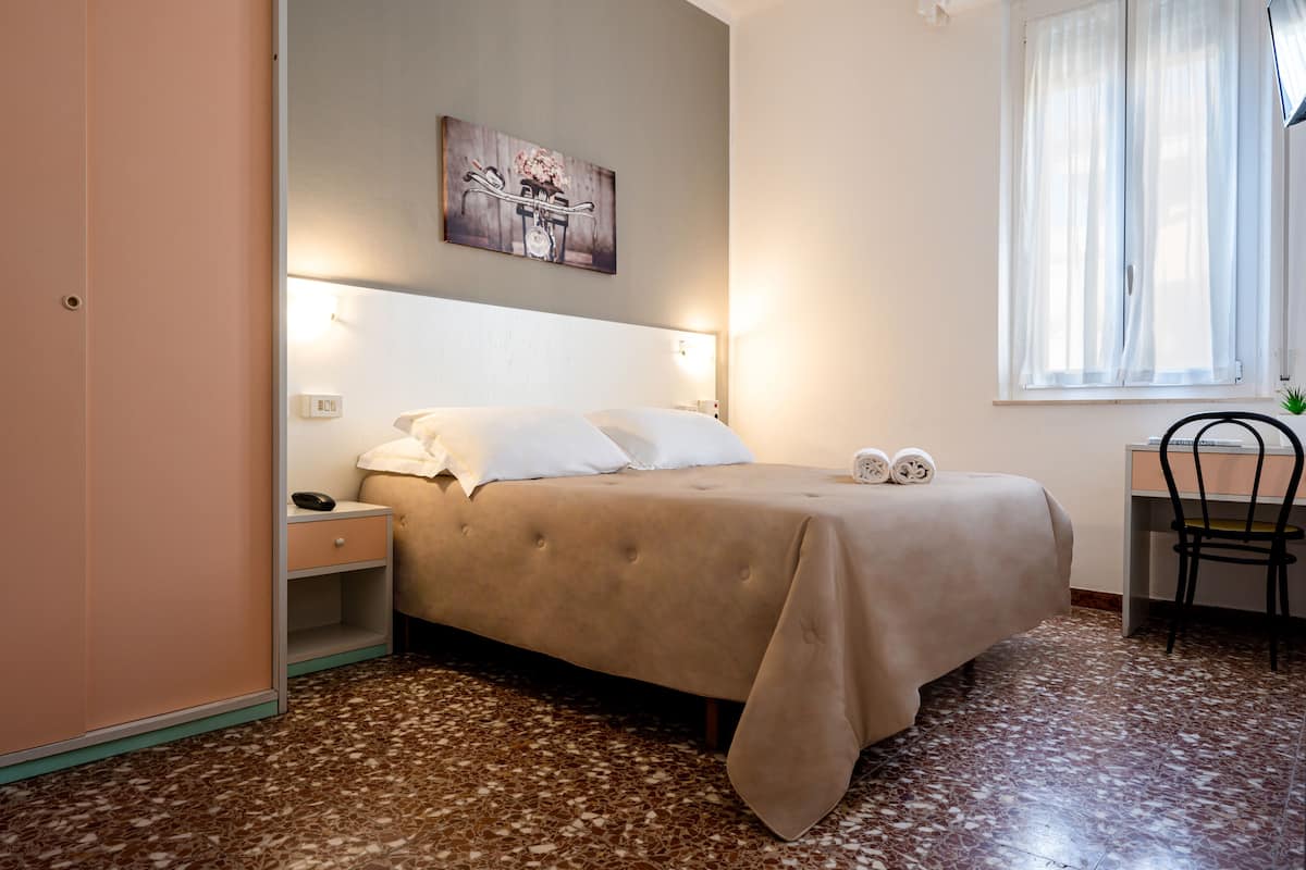 A bedroom with a bed, bedside table, lamp, and a chair.