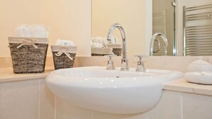 A bathroom with a white sink, two wicker baskets with toiletries, and a mirror reflecting a towel rack.