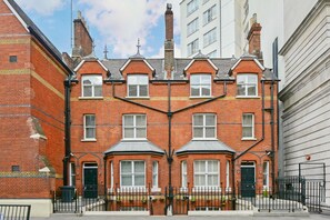 A red brick townhouse with a symmetrical facade, multiple windows, and a central chimney. - LBS Victoria (London)