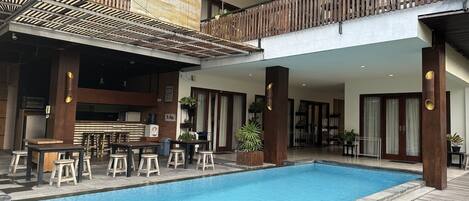 A pool area with a bar and seating, wooden railings, and potted plants.