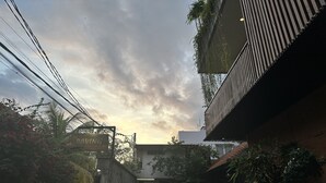 A street view with a building entrance, motorcycles parked outside, and power lines overhead. - The Paving Villa (Canggu)
