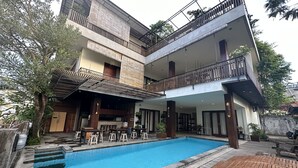 A modern multi-story building with a swimming pool, outdoor seating, and a bar area. - The Paving Villa (Canggu)