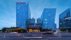 A modern building with a glass facade, a prominent sign reading 'Wanda Realm,' and a well-lit entrance. - Wanda Realm Langfang (Langfang)
