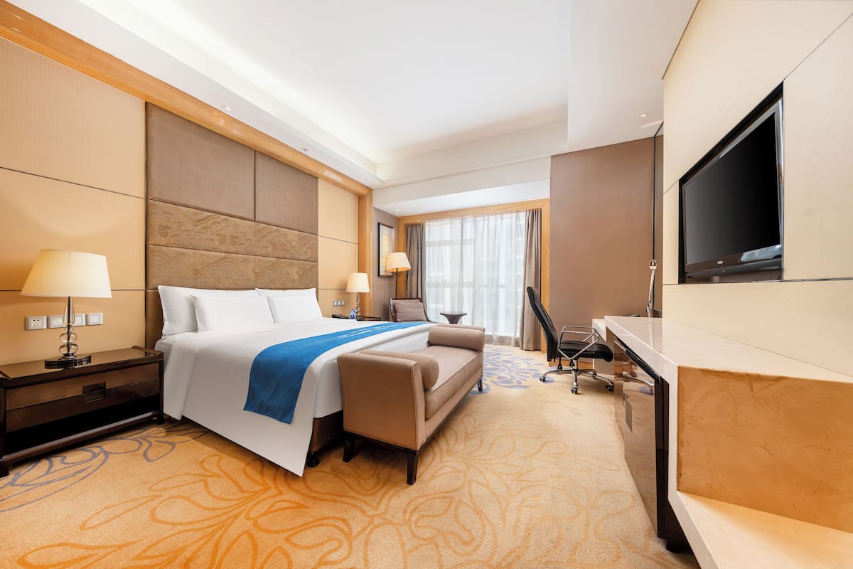 A hotel room with a bed, a desk, a television, and a sofa.