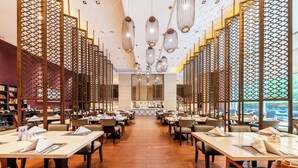 A restaurant with a central bar, multiple tables, and a patterned ceiling. - Wanda Realm Langfang (Langfang)