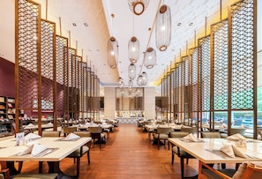 A restaurant with a central bar, multiple tables, and a patterned ceiling. - Wanda Realm Langfang (Langfang)