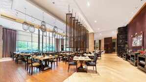 Un comedor amplio con varias mesas y sillas, un separador decorativo y un ventanal con vistas al exterior.