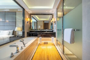 Une salle de bain moderne avec un grand miroir, deux lavabos, une baignoire et une douche à l’italienne.