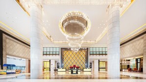 A spacious lobby with a grand chandelier, marble columns, and a reception desk with a floral arrangement. - Wanda Realm Langfang (Langfang)